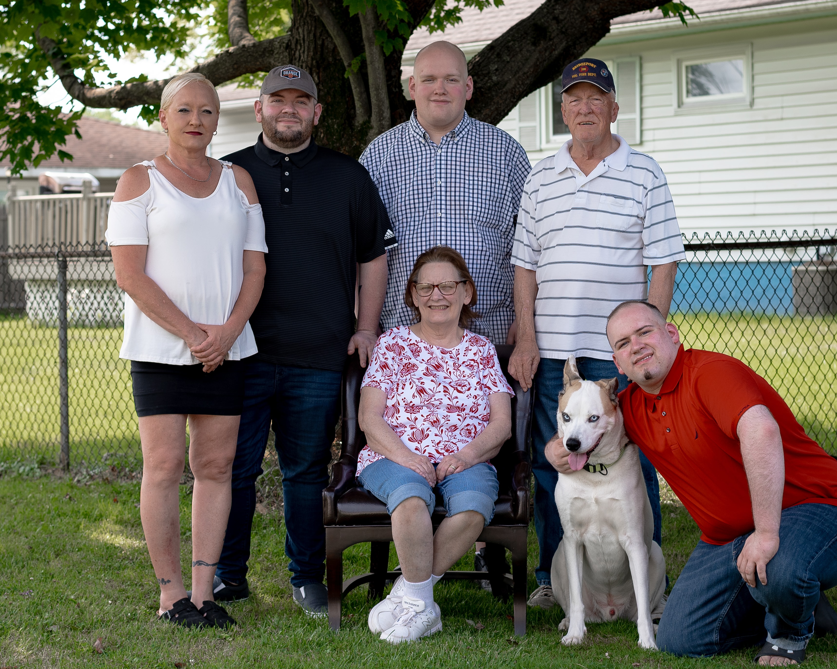 Family posing together in the backyard with their white dog