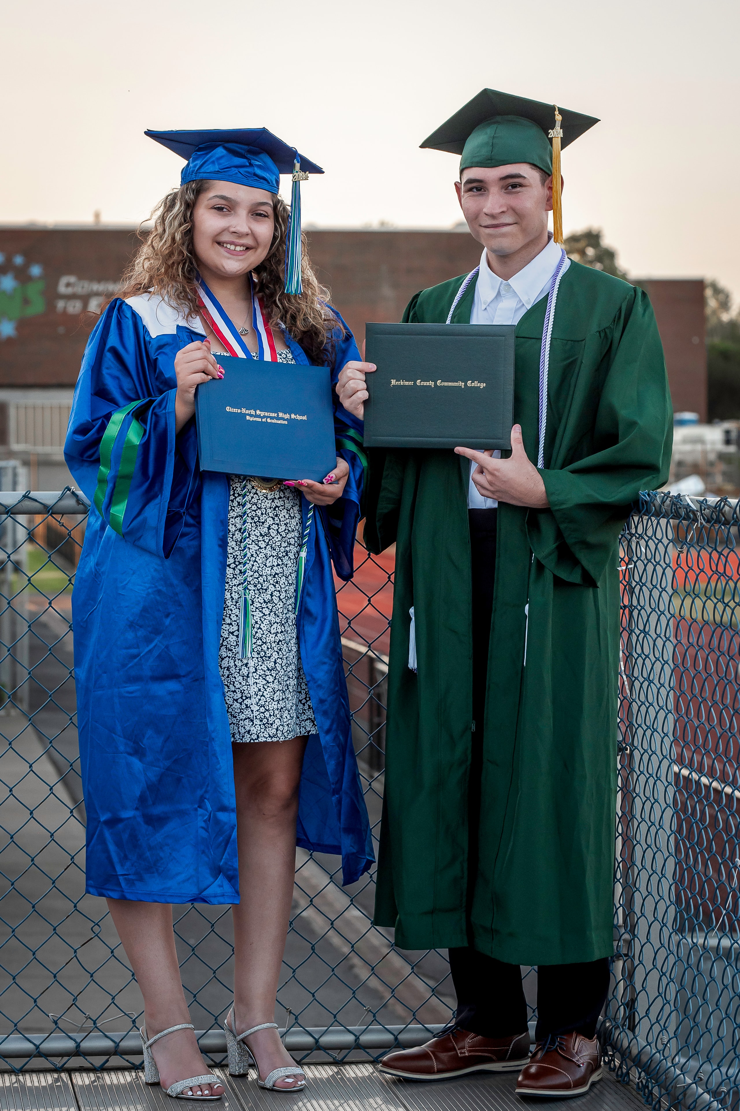 Two graduates holding their diplomas together
