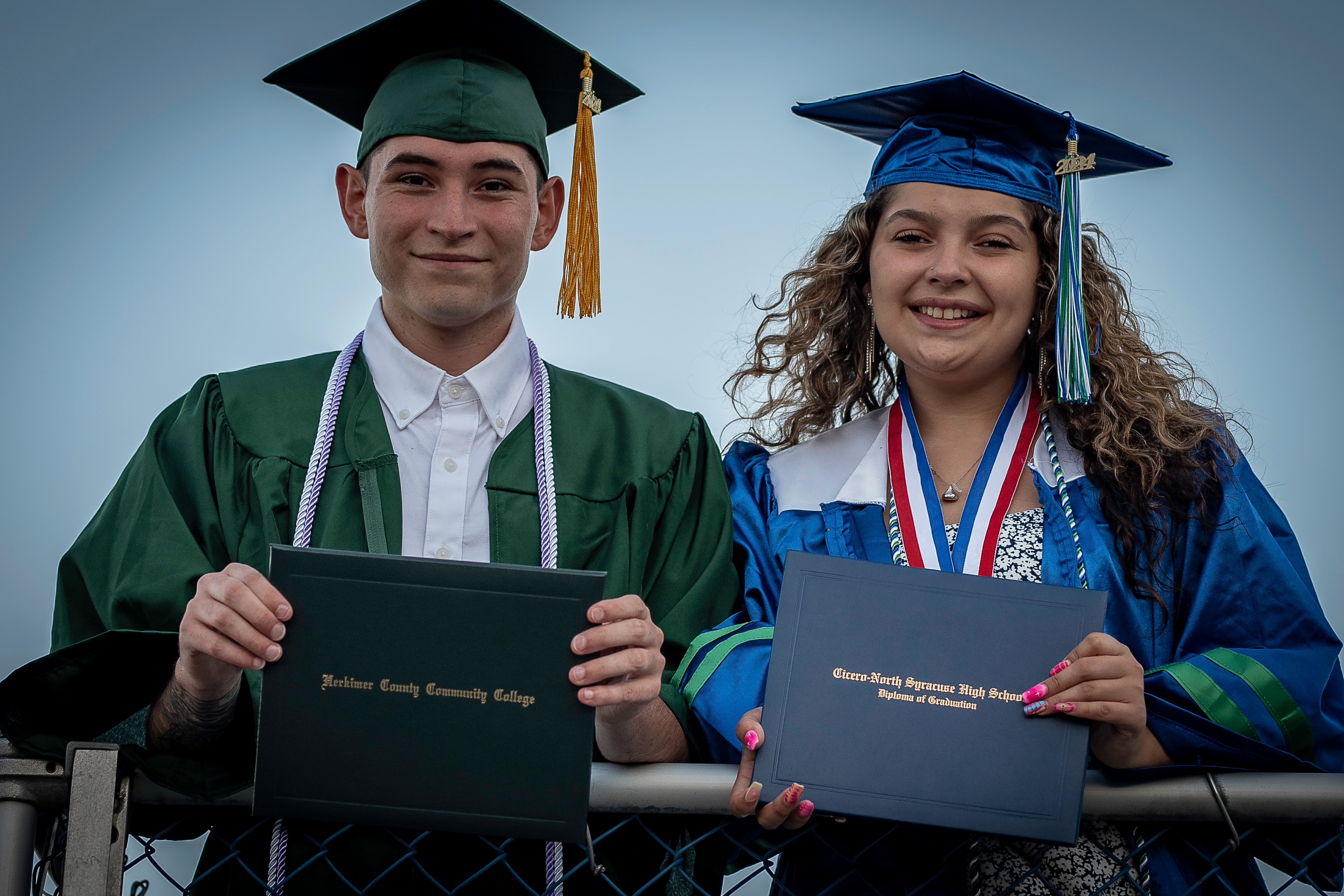 Two graduates celebrating together in caps and gowns